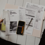 Image of a woman sitting on a floor with a calculator and paper