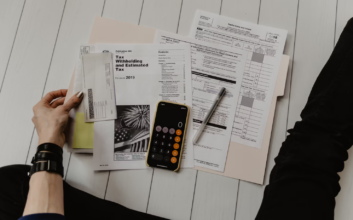 Image of a woman sitting on a floor with a calculator and paper