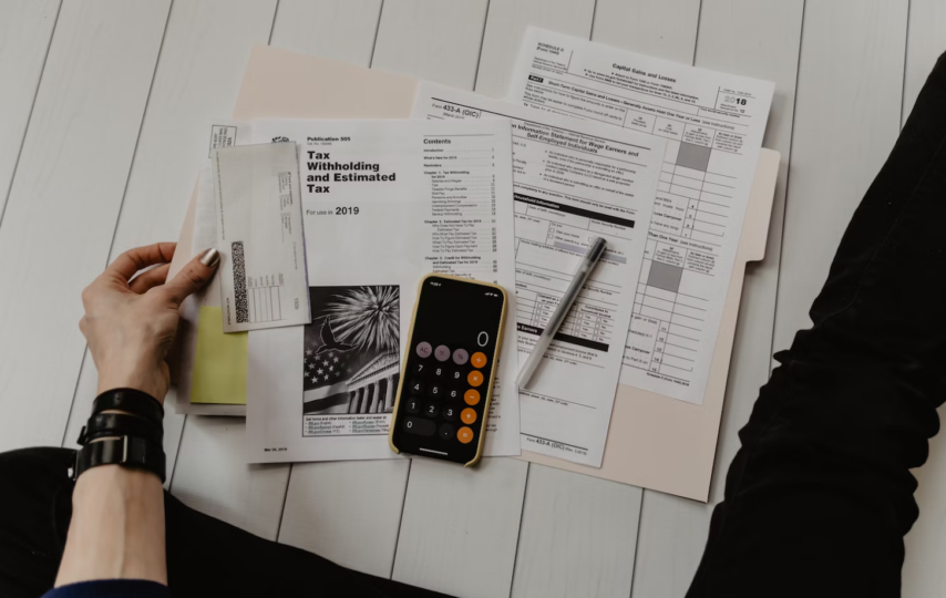 Image of a woman sitting on a floor with a calculator and paper