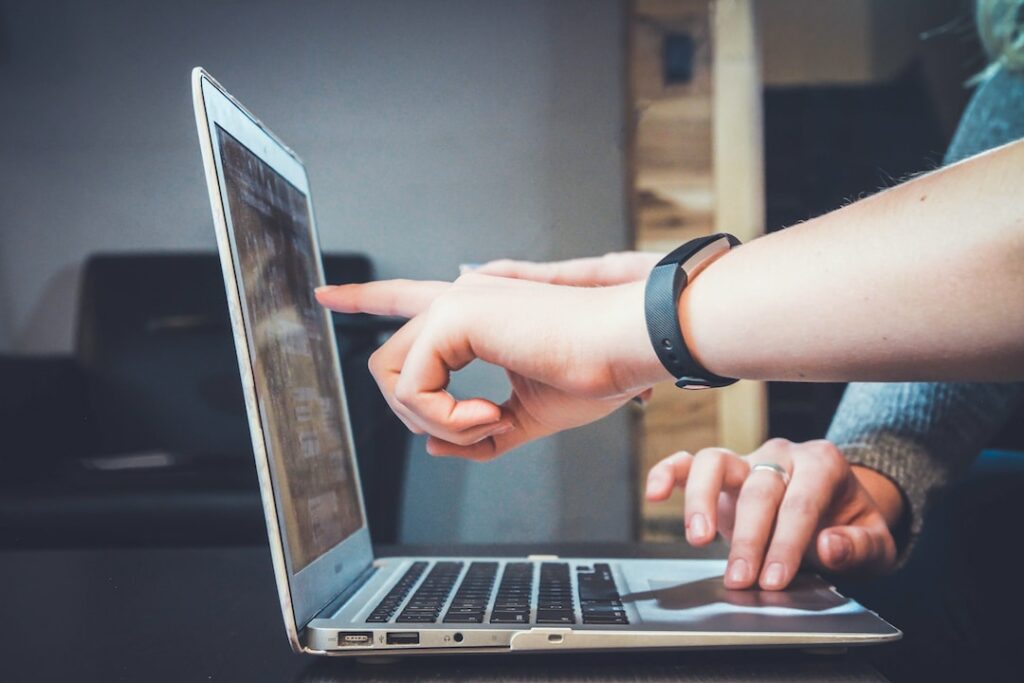 Two people pointing at a laptop analyzing a performance analytics strategy.