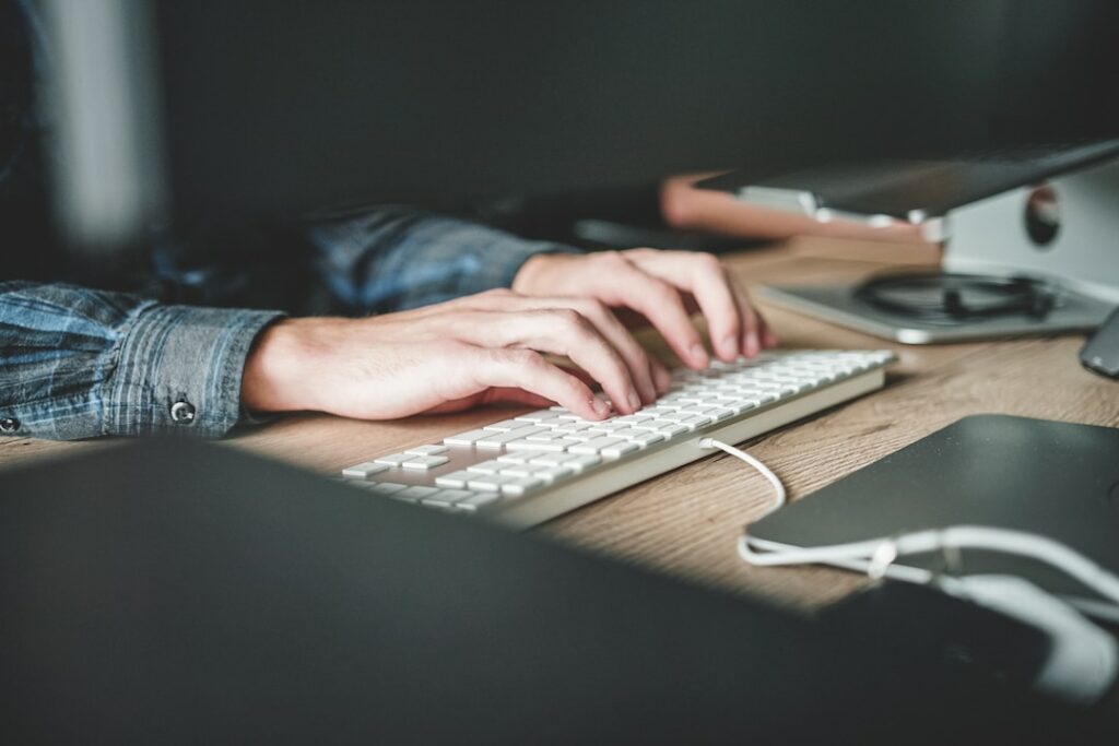 A person typing on a computer keyboard implementing proposal automation software.