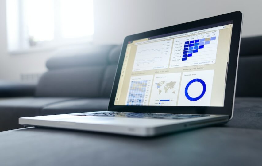 A data visualization dashboard on a laptop screen resting on a grey couch.